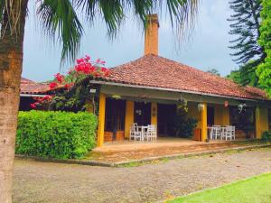 una casa amarilla con mesas y sillas frente a ella en Alugamos para grupos, en Vargem Alta
