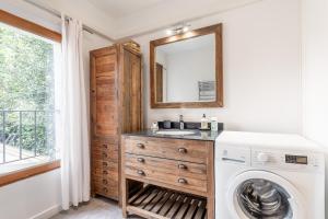 een badkamer met een wastafel en een wasmachine bij Raisin- appartement familial donnant sur la Sorgue in LʼIsle-sur-la-Sorgue