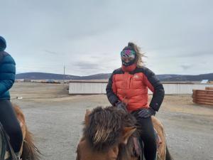 a woman wearing a mask riding on a horse at Energy Guest House in Khyaktil