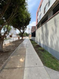 a sidewalk in front of a building with trees at Departamento Acogedor in Lima