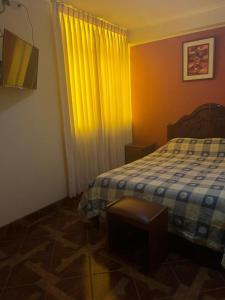 a bedroom with a bed and a yellow curtain at HOTEL ARC&SUITE in Tacna
