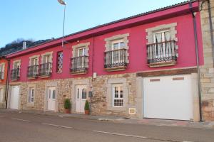 a red building with white garage doors on a street at La Cuadra I in La Pola de Gordón