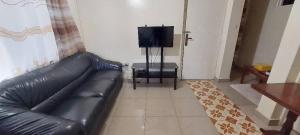 a black leather couch in a living room with a television at Home sweet home in Kigali