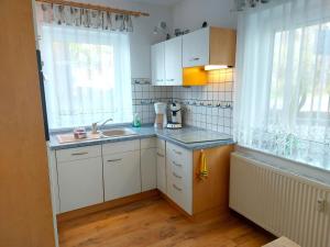 a kitchen with white cabinets and a sink and a window at Komfortferienwohnung Kreideblick in Sassnitz +4 photos