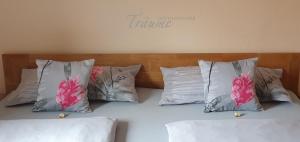 ein Bett mit vier Kissen und rosa Blumen drauf in der Unterkunft Ferienwohnung An der Dorfmauer in Sommerach