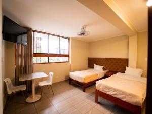 a hotel room with two beds and a desk at Hotel Fundo San Rafael in Nazca