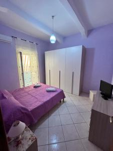 um quarto com uma cama roxa e uma televisão em CasArcobaleno Fronte Policlinico em Messina