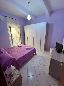 um quarto com uma cama roxa e uma janela em CasArcobaleno Fronte Policlinico em Messina