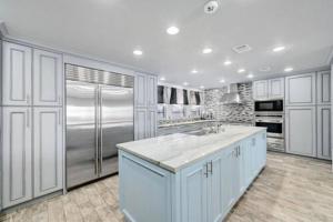 a kitchen with white cabinets and a stainless steel refrigerator at Stunning Waterfront Property Sleeps 12+ in Horseshoe Bay