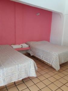Villa Las Garzas في اكستابا: سريرين في غرفة بجدران وردية