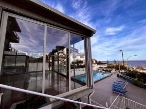 a balcony with a view of a swimming pool and the ocean at Hotel Lachea in Acitrezza