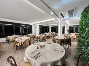 a dining room with white tables and chairs at Hotel Lachea in Acitrezza