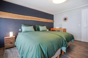 ein Schlafzimmer mit einem großen grünen Bett mit blauer Wand in der Unterkunft Le Gîte de Jade in Dannemarie