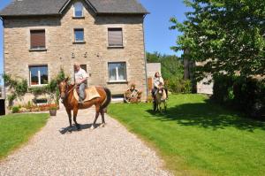 duas pessoas a andar a cavalo em frente a uma casa em Le Mas Capel em Salles-Curan