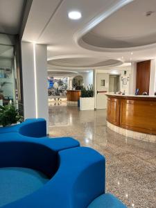 a lobby with blue chairs and a wooden podium at Hotel Lachea in Acitrezza