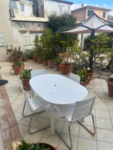 una mesa blanca y sillas en un patio con plantas en Villa Rosa, en Calci