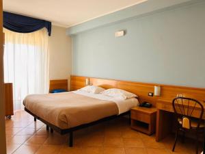 a bedroom with a bed and a chair in it at Hotel Lachea in Acitrezza