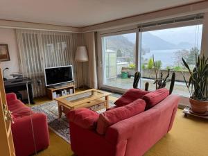 sala de estar con sofá rojo y ventana grande en Charming Apartment w/Terrace on Lake and Mountain en Weggis
