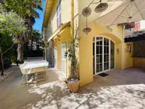 żółty dom ze stołem na dziedzińcu w obiekcie L'Eden House - Maison hyper centre plages 2min à pied piscine w mieście Antibes