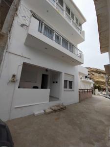 a large white building with a balcony and a parking lot at Studio George - near the beach in Matala