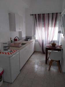 a kitchen with white cabinets and a table and a window at Studio George - near the beach in Matala