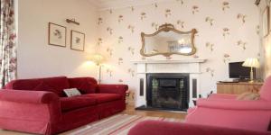 sala de estar con sofá rojo y chimenea en Hill House Clifden, en Clifden