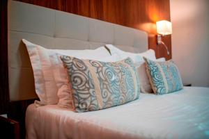 a bed with white pillows and a white headboard at Ananda Pousada in Pirenópolis