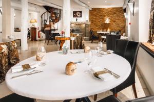 uma sala de jantar branca com uma mesa e cadeiras brancas em Logis L'Auberge - Maison Glenn Anna em Sainte Anne d'Auray