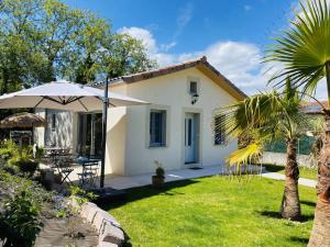 Biały dom z parasolem i ogródkiem w obiekcie Le Saint Marin w mieście Chatuzange-le-Goubet