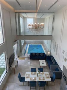 شاليه رويال الخبر - Royal Resort AL Khobar في الخبر: مسبح في وسط غرفة مع طاولات وكراسي