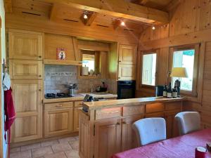 a kitchen with wooden cabinets and a counter with chairs at Chalet familial sur les pistes in Megève
