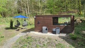 a small wooden shed with chairs and an umbrella at Barn near Colne for Leisure or Business in Colne