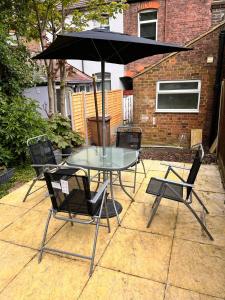 uma mesa e cadeiras com um guarda-sol num pátio em Visit Luton With This 2 BR Rental - Sleeps 6 em Luton