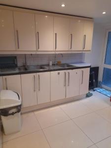 a kitchen with white cabinets and a sink at RAYAN'S LODGE STRATFORD in London