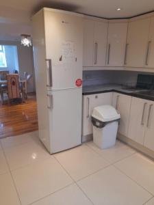 een keuken met een witte koelkast en een tafel bij Rayan's Lodge Stratford London by OYO in Londen