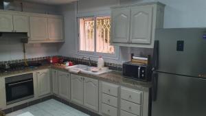 a kitchen with white cabinets and a stainless steel refrigerator at Villa Sérénité, Yasmine Hammamet in Hammamet