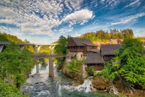 un puente sobre un río con casas y un puente en Aria Room - Rastoke en Slunj