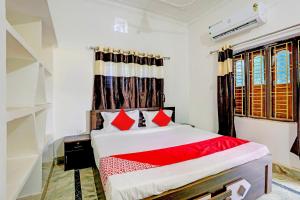1 dormitorio con 1 cama con almohadas rojas en Super OYO Flagship Namaskar Cozzy Cottage, en Bhubaneshwar