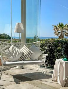 ヴィッラフランカ・ティッレーナにあるAppartamenti Vacanze Villa Meoの白いベンチ(枕付)、海を望むバルコニー