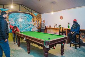 a group of people standing around a pool table at Gypsy Hostel & Backpackers in Pokhara