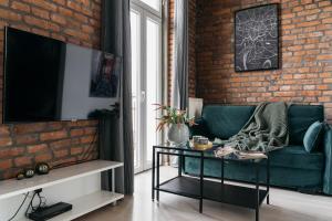 - un salon avec un canapé vert et un mur en briques dans l'établissement Rotunda Apartment by LoftAffair, à Cracovie