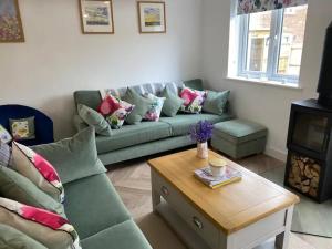 a living room with a green couch and a coffee table at Bluebells, Little Snoring in Fakenham