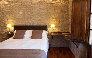 a bedroom with a bed and a stone wall at Hotel del Sitjar in Calaceite