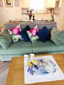 a living room with a couch with flowers on a table at Bluebells, Little Snoring in Fakenham