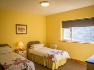 a yellow room with two beds and a window at Lough Fee Renvyle in Renvyle