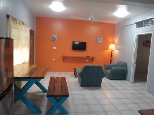 salon z pomarańczowymi ścianami oraz stołem i krzesłami w obiekcie Rachel Land w Caye Caulker