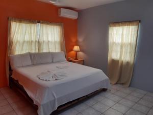 1 dormitorio con 1 cama con sábanas blancas y ventanas en Rachel Land, en Caye Caulker