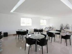uma sala de jantar com mesas, cadeiras e janelas em O apartamento queridinho de luxo em Lagoa Santa