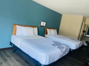 Super Inn Downtown في باردستاون: سريرين في غرفة بجدران زرقاء