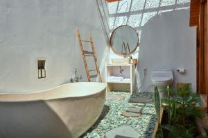 La salle de bains est pourvue d'une baignoire, de toilettes et d'un miroir. dans l'établissement Plumeria NP, à Nusa Penida